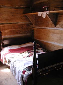 [ Bedroom Where Bridget and Mrs. Donnelly Were Sleeping, Lucan and Area Heritage and Donnelly Museum, The museum's log home is a recreation of the original Donnelly cabin that burned the night of the murders in 1880.  Copyright Great Unsolved Canadian Mysteries Project, Jennifer Pettit,   ]