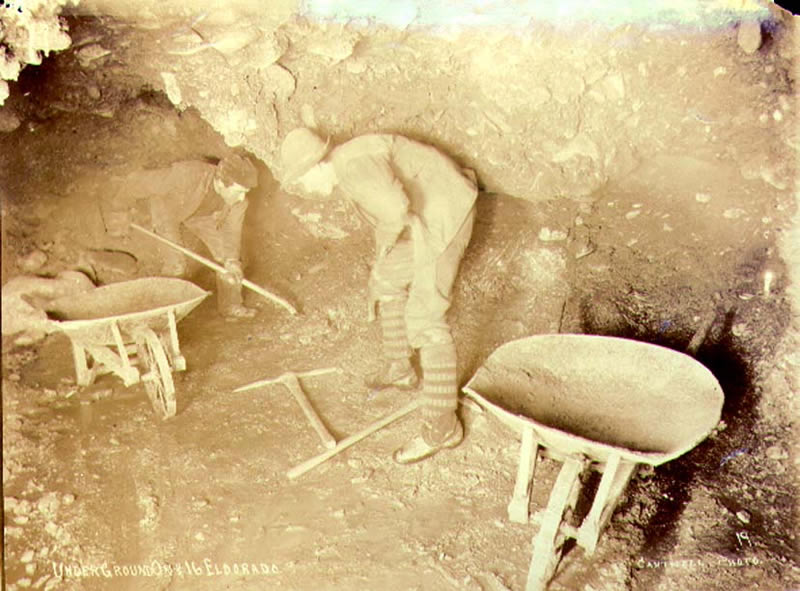 Miners at work with pickaxes and shovels in underground gold mine, No