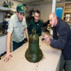 Personnel de Parcs Canada examinent la cloche de l’Erebus avec un archéologue du Gouvernement du Nunavut