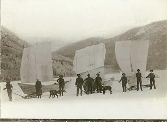 [ Klondikers crossing frozen Lake Laberge with boats and sleds outfitted with sails ]